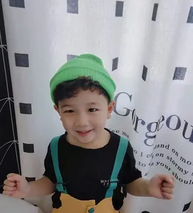Close-up of a vibrant green short knitted beanie hat worn by a child model