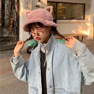 Cute pink plush bucket hat with cat ears worn by model in urban street setting