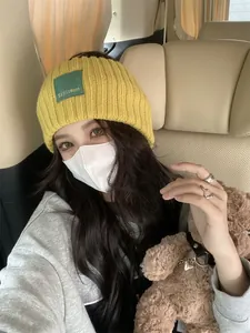 Trendy yellow knit headband with letter patch worn by an Asian woman in a car setting
