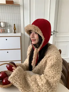 Close-up of a stylish red knitted trapper hat featuring soft beige faux fur trim for winter.