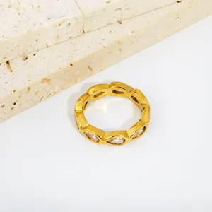 Macro detail of a gold-plated stainless steel ring featuring teardrop-shaped white zircons