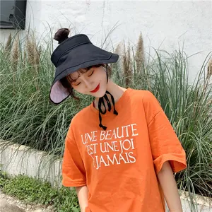 Femme portant un chapeau de soleil en lin noir et un t-shirt orange pour l'été