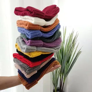 A vibrant stack of colorful ribbed knit beanies held against a bright minimalist background