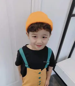 Close-up of a child wearing a bright orange short knitted beanie skull cap for autumn