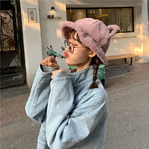 Detailed shot of a cute purple faux fur bucket hat with ears worn by a model in a street setting