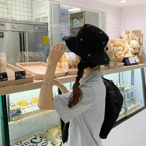 Vista de estilo de vida de un sombrero de pescador negro con bordado blanco en café
