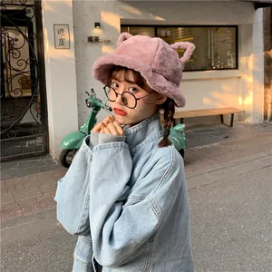 Model wearing a cute pink plush bucket hat with cat ears in a street setting