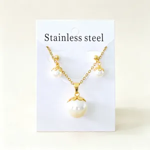 Detalle de elegante conjunto de collar y pendientes de acero dorado con perlas blancas