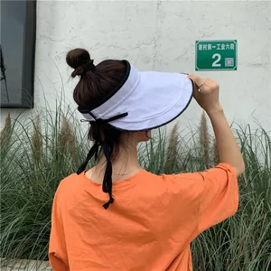 Gros plan d'un élégant chapeau visière blanc avec bordure noire et ruban décoratif