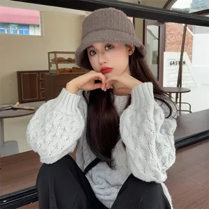 A stylish brown plush bucket hat worn by a female model in a cozy cafe setting view