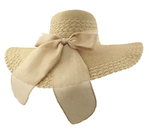 Close-up detail of a beige straw sun hat featuring a large bow and elegant wavy brim design