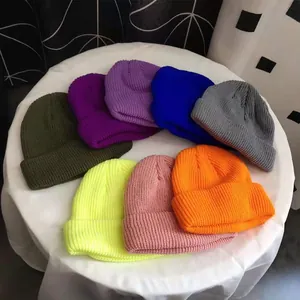 Collection of vibrant colorful knitted beanie hats displayed on a white round table.