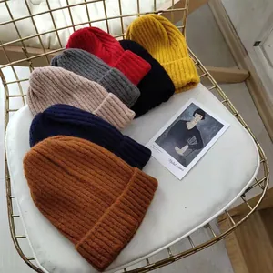 A collection of colorful ribbed knit beanies displayed on a white cushion for winter fashion.