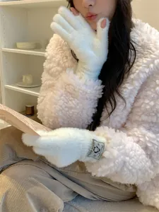 Dettaglio ravvicinato di guanti invernali in peluche bianco con simpatica etichetta pinguino.