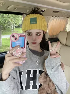 Close-up of yellow knitted headband with green label worn by model in car setting