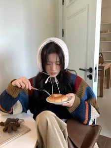Asian model wearing white lamb wool earmuffs with ribbon tie in a cozy cafe setting