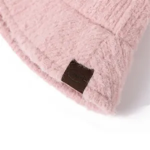 Close-up of pink fluffy mohair bucket hat with brown M-UNION leather patch detail.