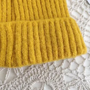 Detailed macro view of mustard yellow rib-knit texture on a cozy winter beanie hat.