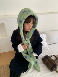 Detail showing a plush green hooded scarf with floral patterns worn in a lifestyle setting