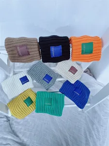 Detailed view of colorful ribbed knit headbands with square logo patch in various shades