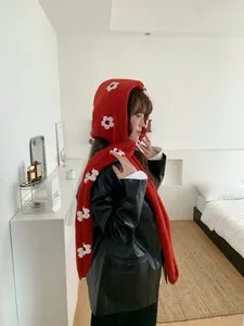 Sciarpa con cappuccio in peluche rosso con fiori bianchi indossata da una modella