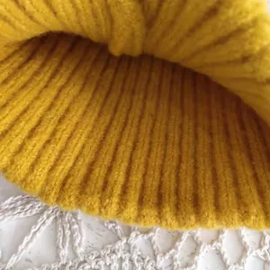 Macro view of a warm yellow ribbed knitted beanie hat detail for winter