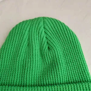 Macro view of bright green rib-knit beanie showing soft wool texture