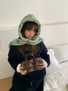 Plush green hooded scarf with star patterns worn by a model in a cozy indoor setting
