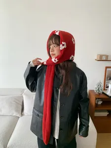 Dettaglio di una sciarpa in maglia rossa con cappuccio e motivo floreale su modella