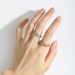 Detailed view of gold and silver bezel-set rings with round white zircons worn on a hand