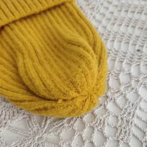 Macro detail of a bright yellow knitted beanie showing soft wool texture