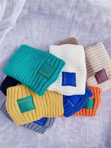 Close-up of vibrant knitted headbands featuring stylish letter patches for winter warmth