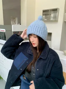 Nahaufnahme einer weichen hellblauen Strickmütze mit süßem Bommel für den Winter