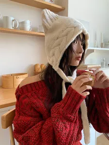 Detailed close-up of a cute white knitted cat ear beanie with braided ties on a model