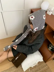 Vista dettagliata di una comoda sciarpa con cappuccio in maglia grigia con fiori su modella.