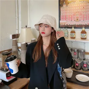 Close-up of a stylish beige pleated bucket hat worn by a model in a cafe setting