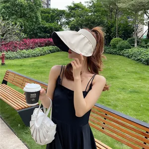 Frau mit beigem Sonnenhut mit breiter Krempe im Park, Outdoor-Lifestyle-Detailansicht.