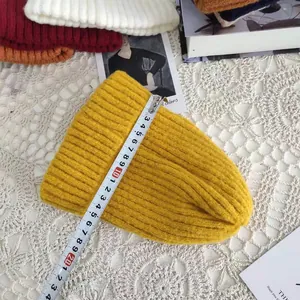 Detailed close-up of a yellow knitted beanie hat with a tape measure showing product size.