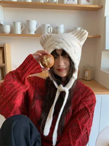 Close-up of a white knitted cat ear hat with earflaps and long decorative tie strings