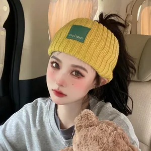 Stylish yellow knitted headband for women, cozy winter ear warmer with logo patch detail