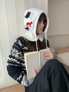 Cozy lifestyle detail of woman wearing a white cartoon knitted balaclava while reading