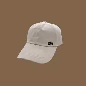 Vue détaillée d'une casquette de baseball beige avec broderie DYJ et bord surpiqué