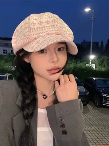 Detail view of pink knit octagonal newsboy hat worn by model in outdoor night setting