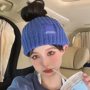 Stylish blue ribbed knitted headband with pipisweet patch worn by a model in a car