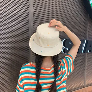 Vista trasera de un gorro de pescador bordado beige usado por una modelo en exteriores