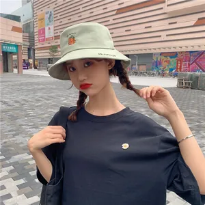Girl wearing a light green bucket hat with cute pumpkin embroidery in an outdoor setting