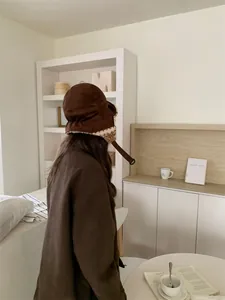 Détail du chapeau trappeur en daim marron avec doublure polaire chaude et bride.