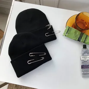 Dettaglio di berretti hip-hop neri con spille da balia decorative e anelli d'argento