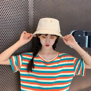 Modelo luciendo un gorro tipo pescador crema con letras bordadas de colores en verano
