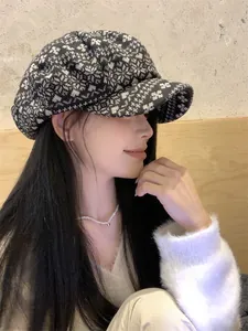 Side view of an Asian woman wearing a black and white snowflake patterned newsboy hat